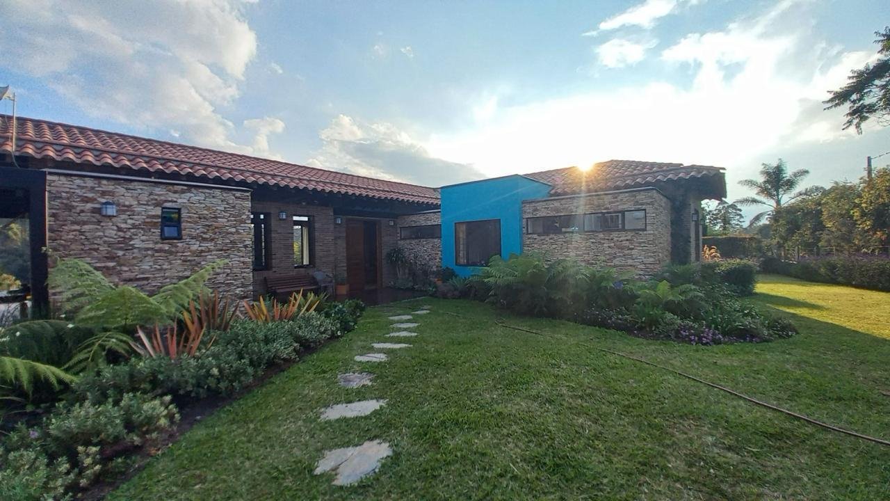 Fachada de la casa campestre al atardecer, rodeada de jardín